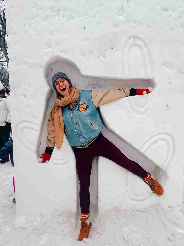 a girl stands inside an ice sculpture carved out in the shape of a person