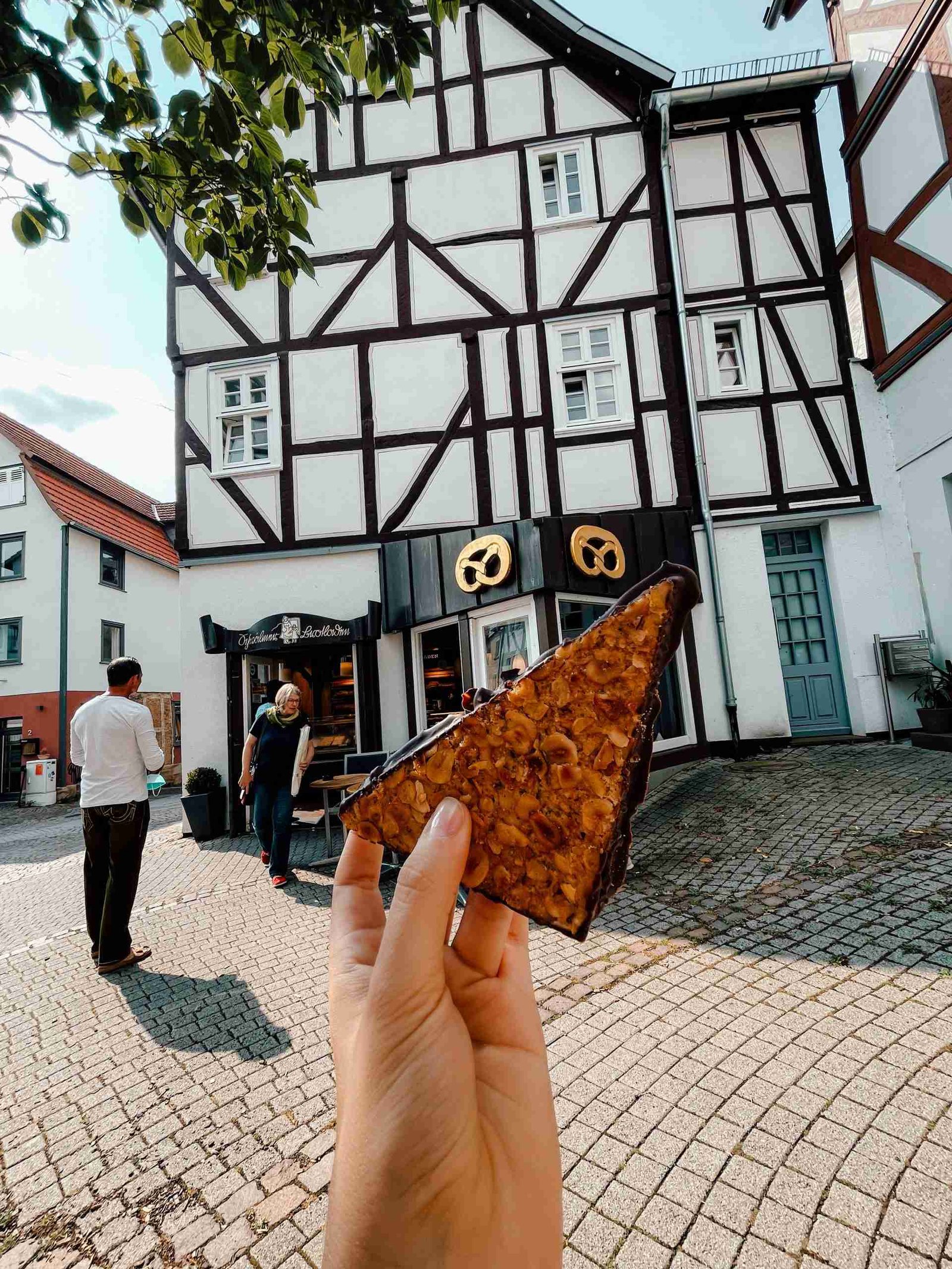 Someone holding a pastry in front of an adorable bakery in Fritzlar