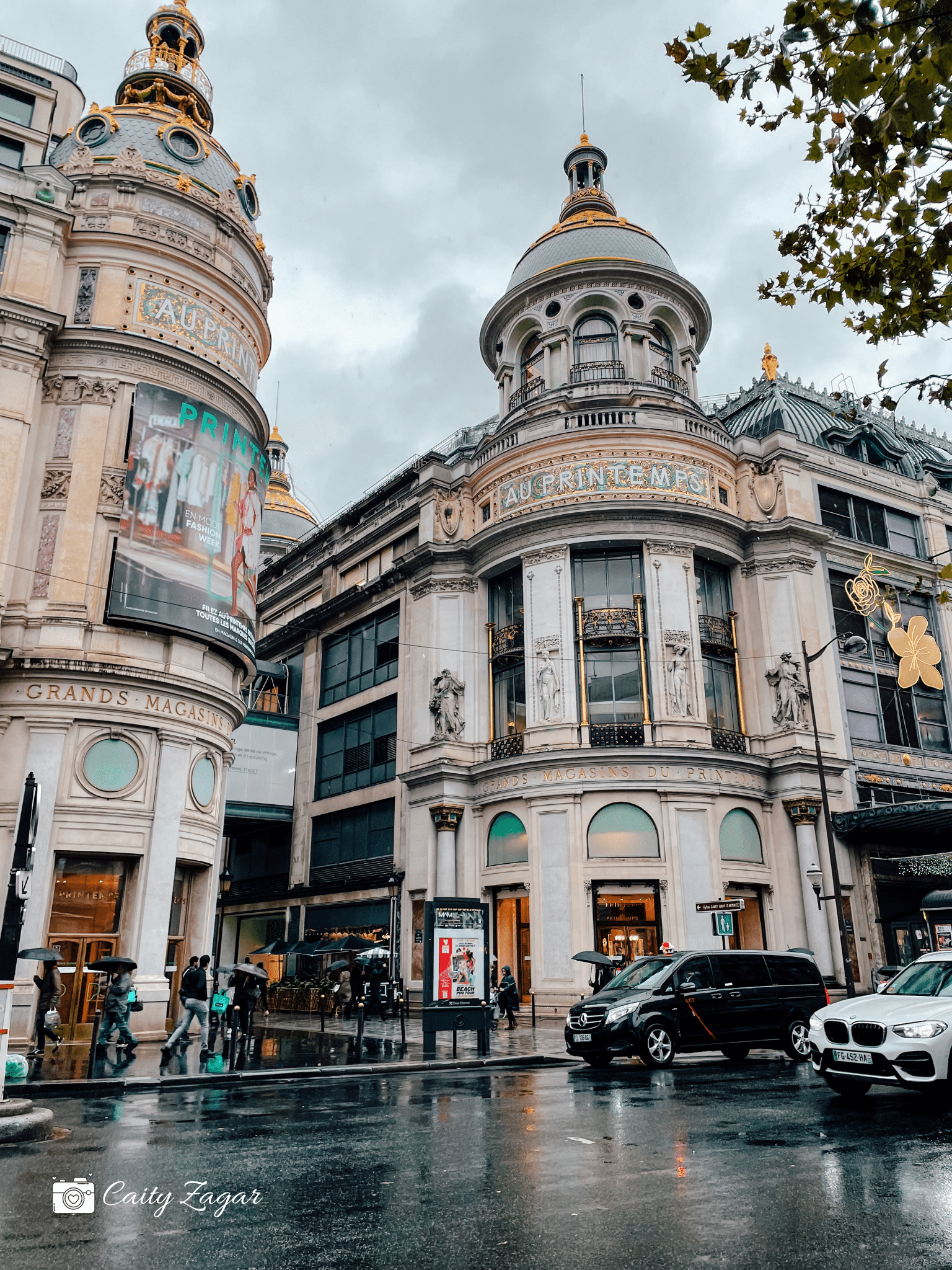 The beautiful gold details on the store front of the Printemps department store on a rainy day