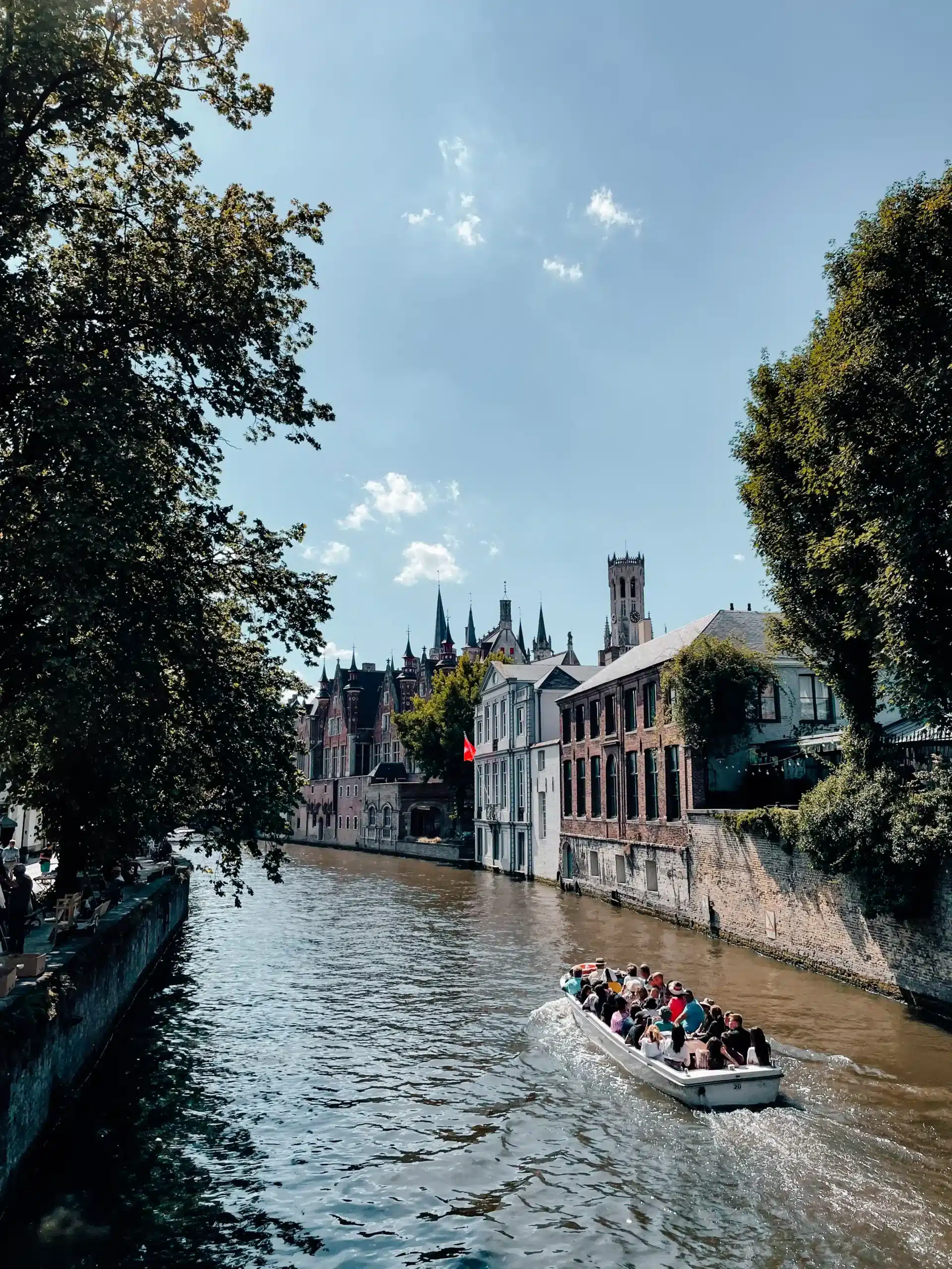 A boat riding the canals in Bruges on a sunny day 