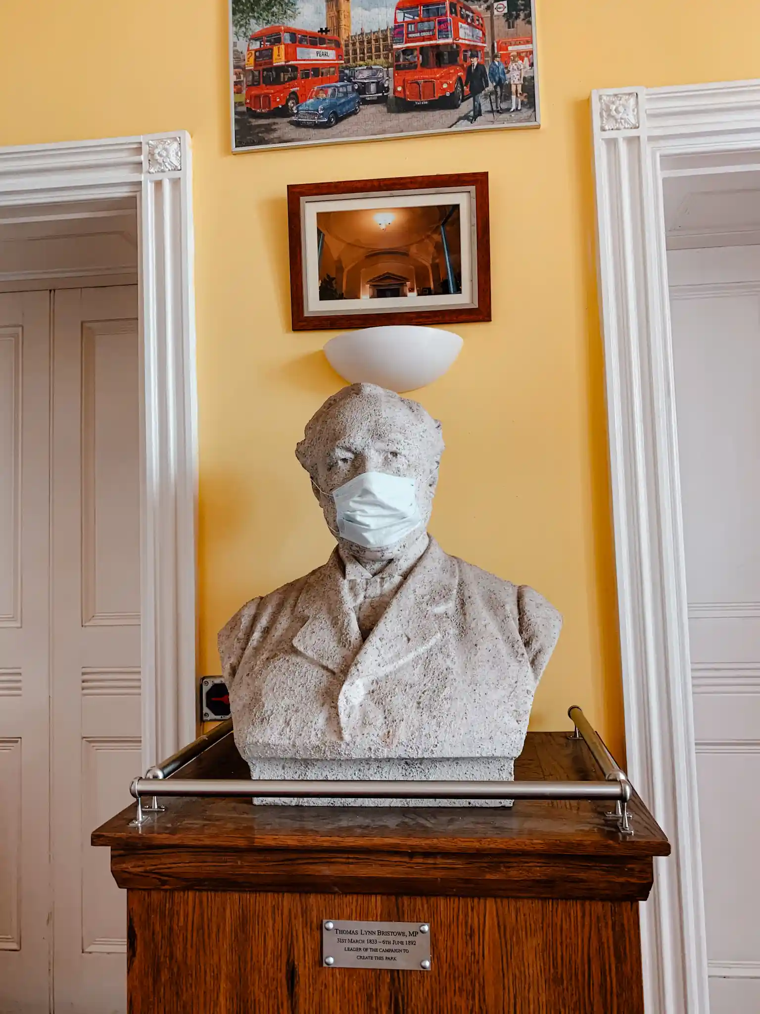 a statue in London with a face mask