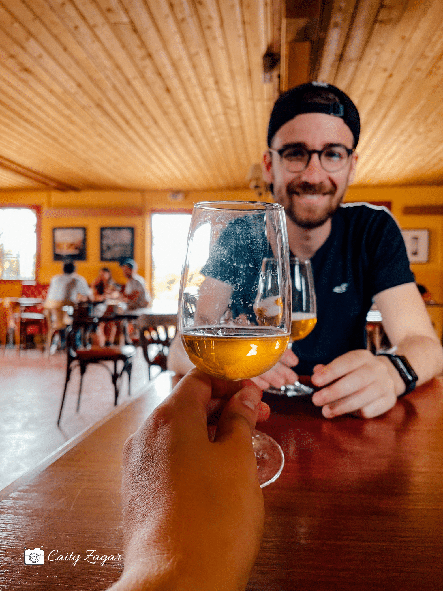 Someone holding up a glass of cider in a dining room during a cider tasting.
