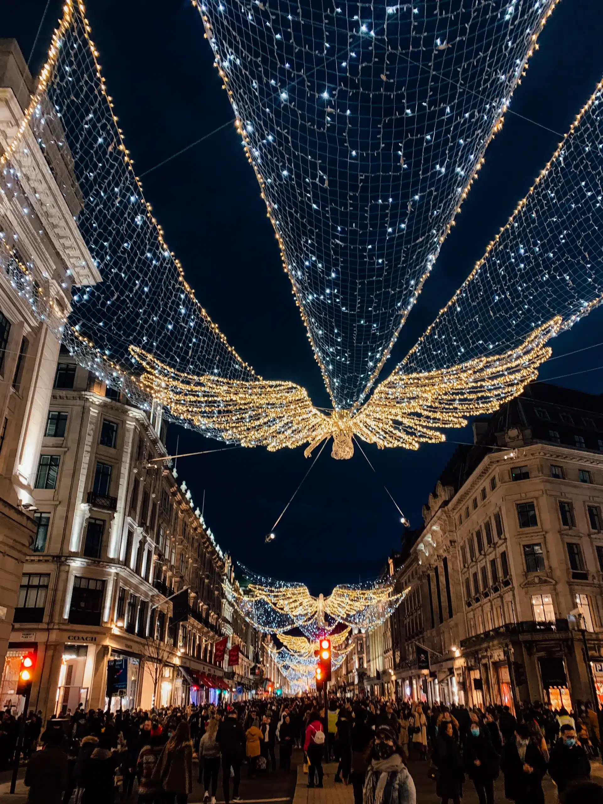 Large, glowing angel-shaped Christmas lights hanging over Regent Street in London - the most picturesque, warm and festive spot during the Christmas season