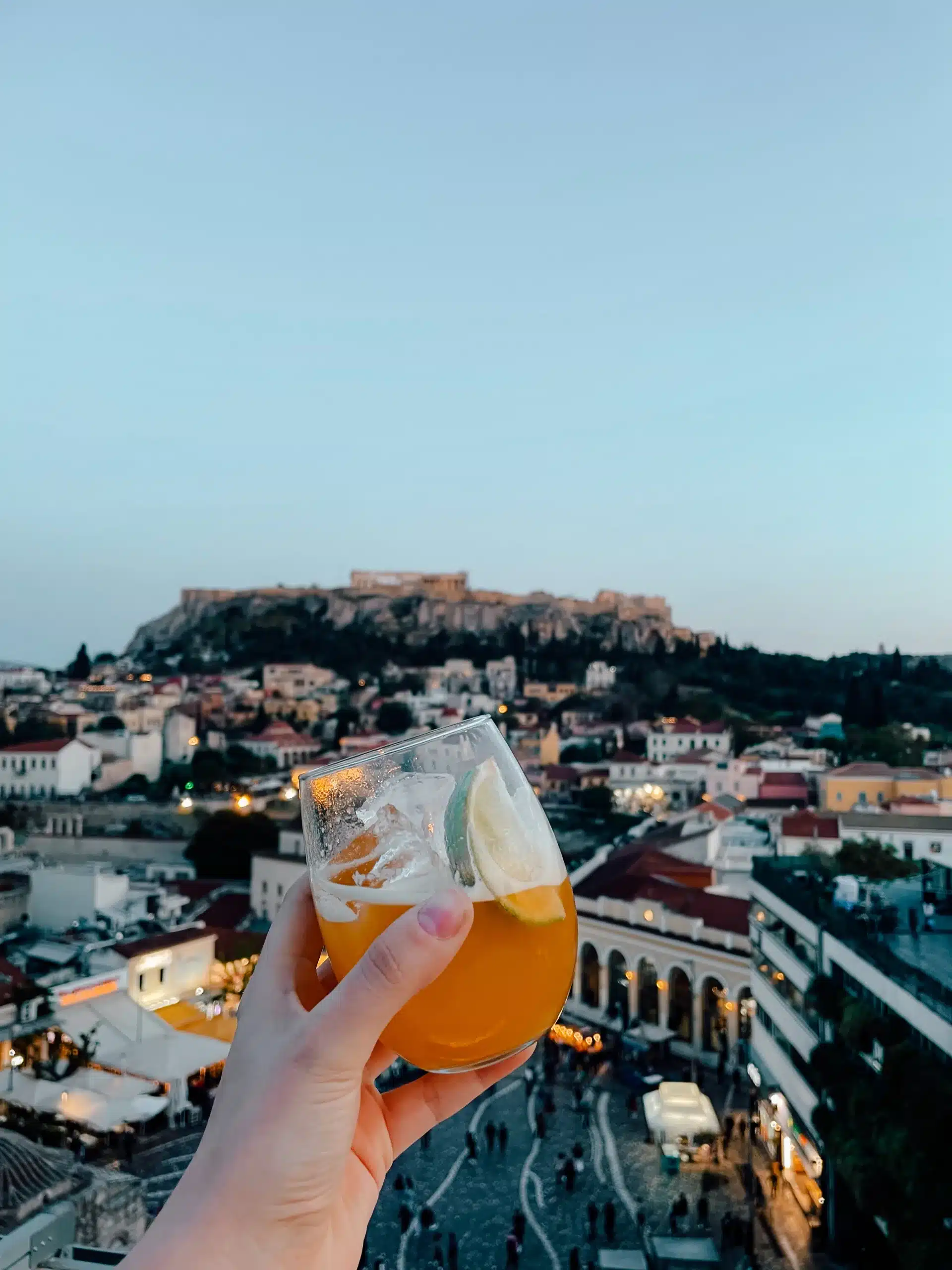 Someone holding their cocktail drink on a beautiful rooftop terrace in Athens