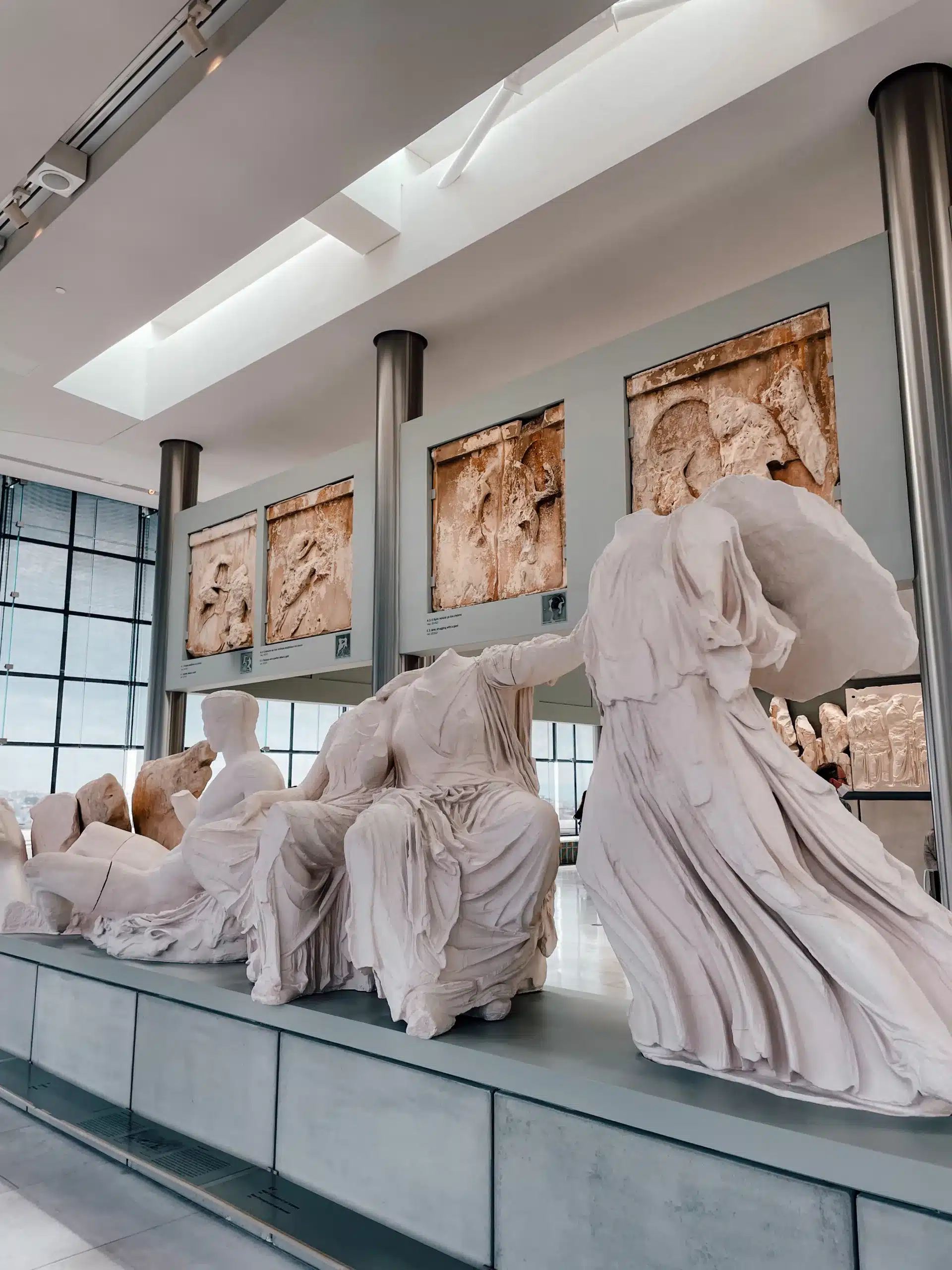 Several stone statues, original relics from the Acropolis, sit inside the Acropolis Museum in Athens