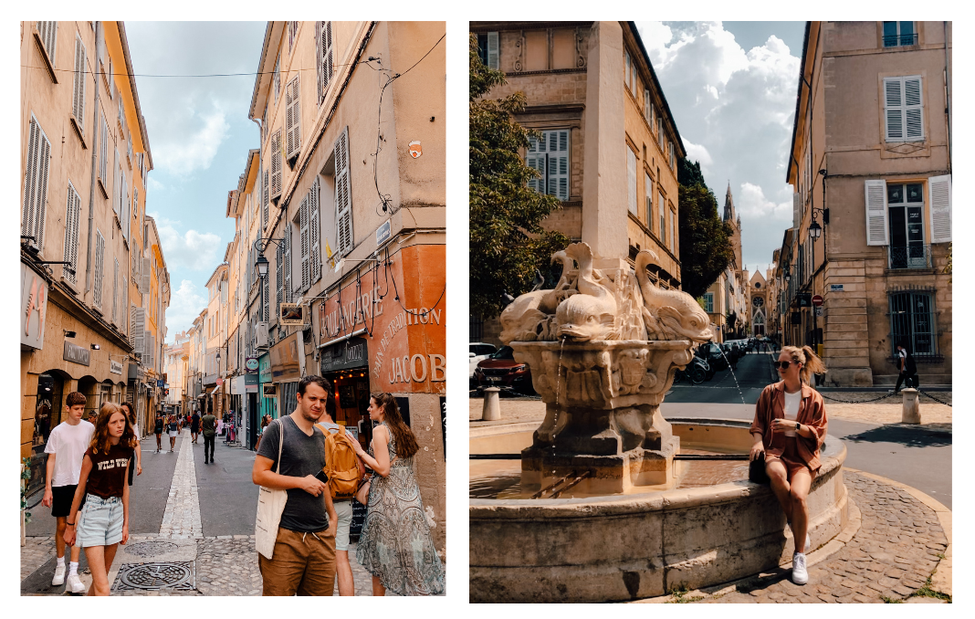 The narrow streets of Aix-en-Provence on a sunny day. A girl sits beside a fountain in a roundabout.