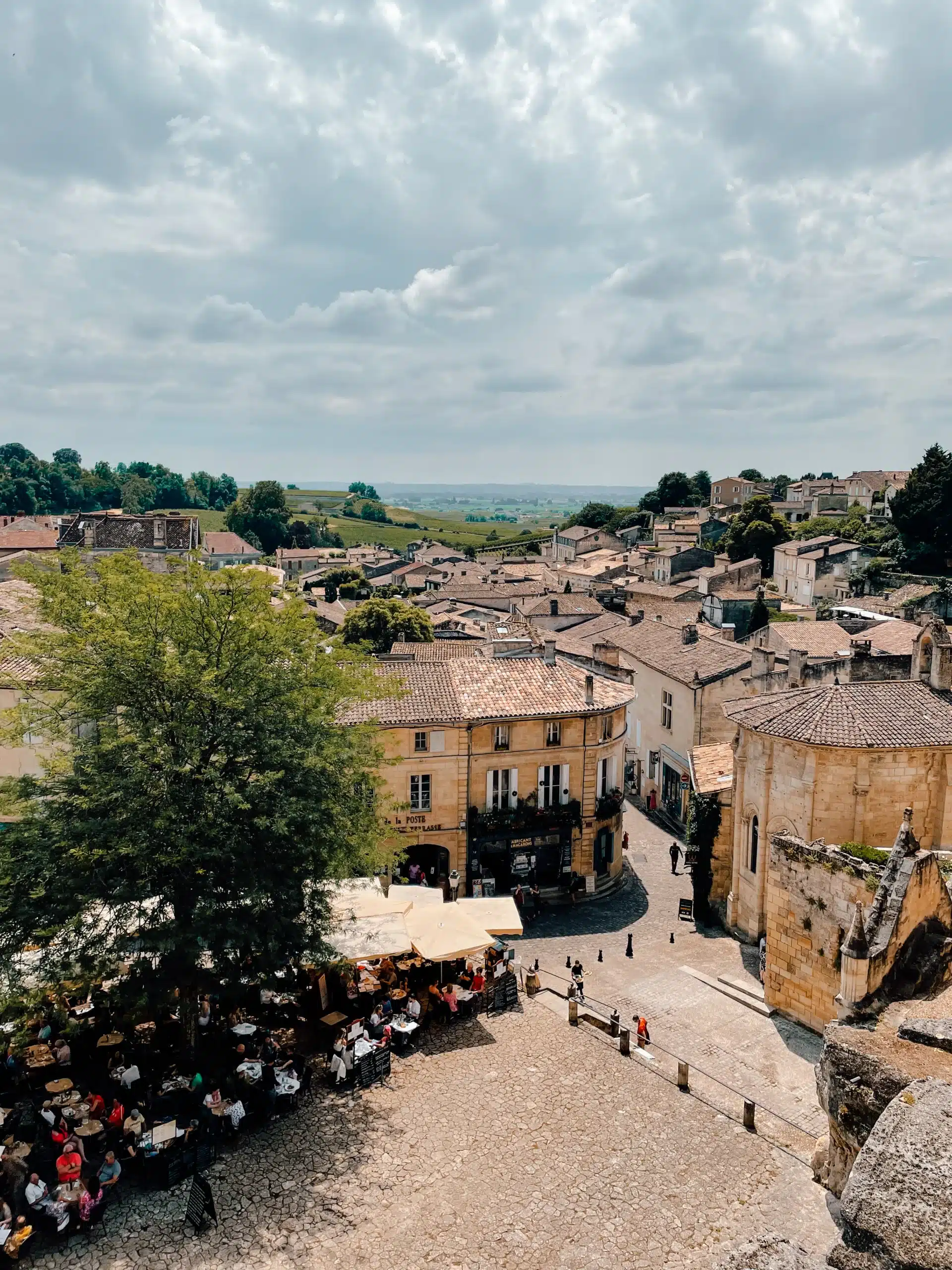 Overlooking the main square in St. Emilion with people huddled under terraces enjoying the summer day 