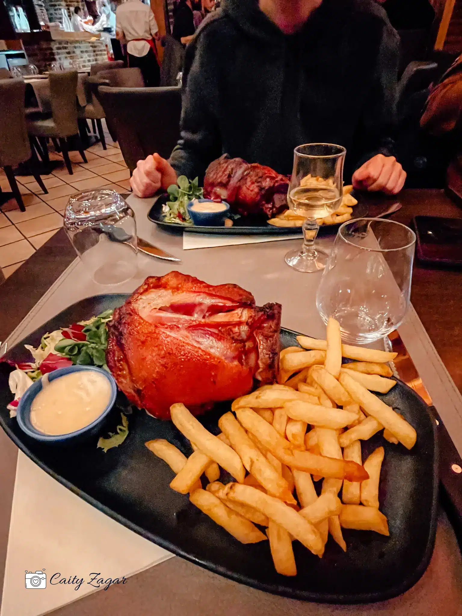 a massive piece of pork served with fries inside a tavern