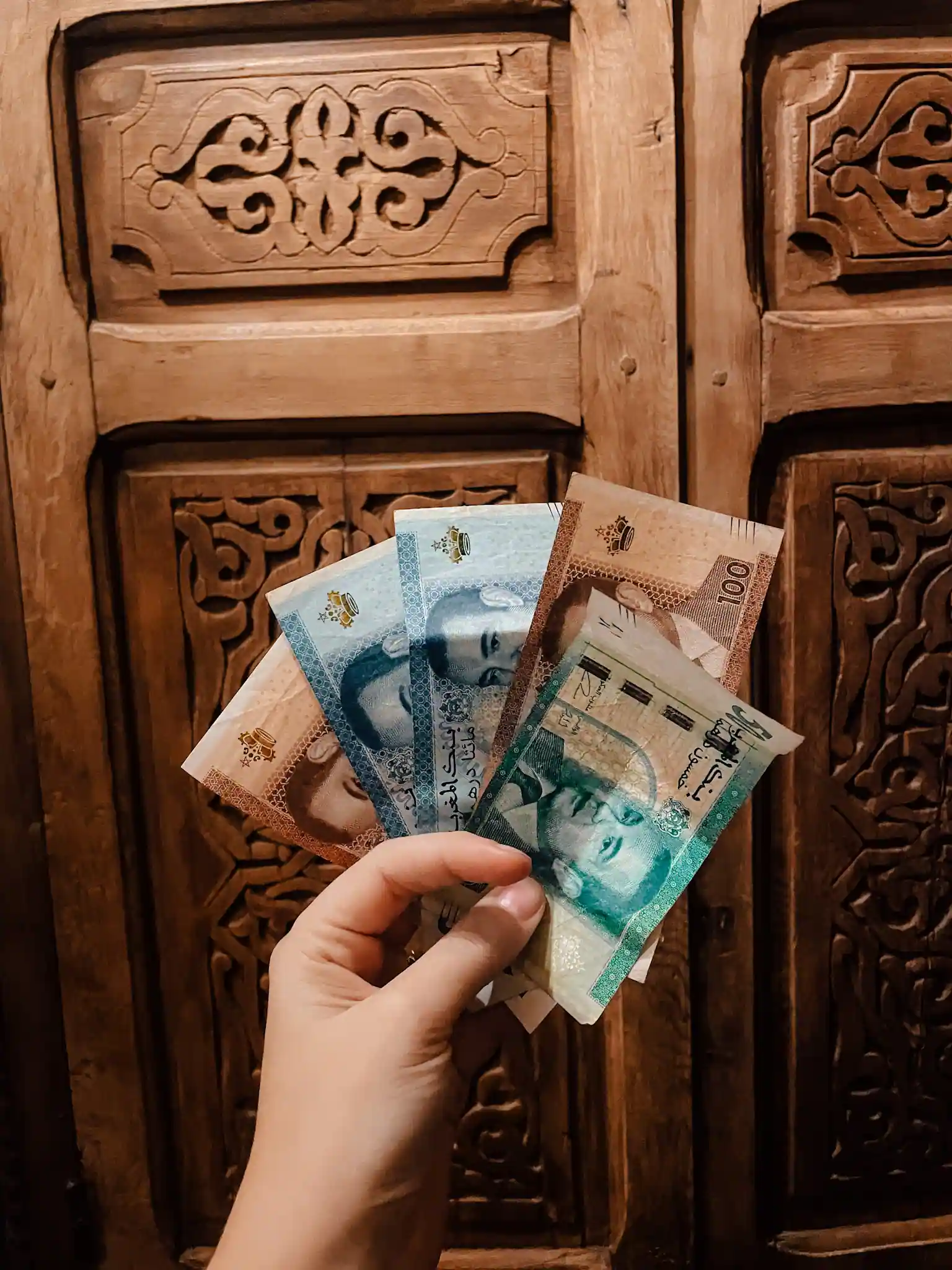 Someone holds a handful of Moroccan dirhams in their hand spreading them into a fan shape 